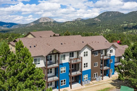 A large apartment complex with balconies and a mountain in the background.