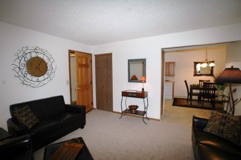 A living room with a couch, chair, and a clock on the wall.