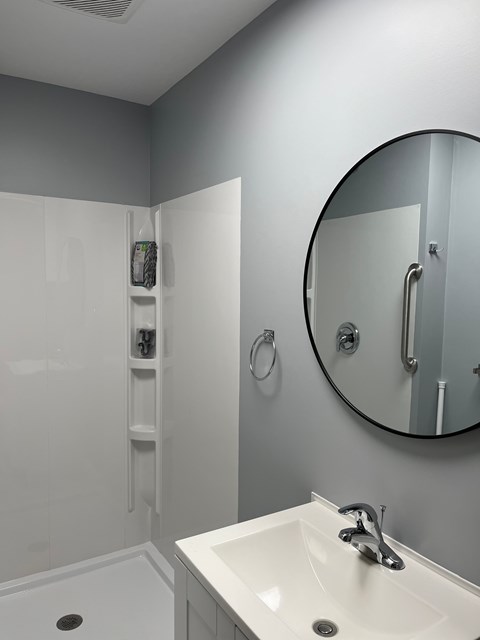 A bathroom with a white sink and a round mirror.