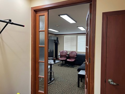 A room with a mirror, chairs, and a table.