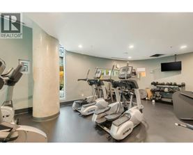 A gym with a row of treadmilers and elliptical machines.