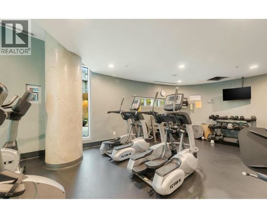 A gym with a row of treadmilers and elliptical machines.