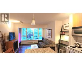 A living room with a couch, a television, and a window with a view of a city.