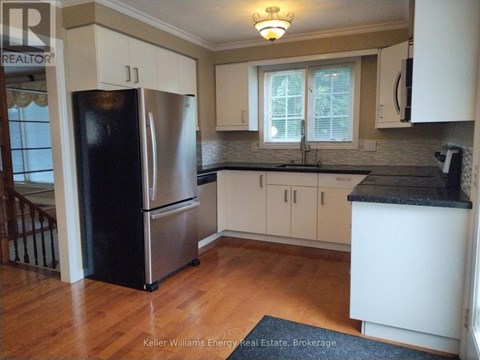 A kitchen with a black fridge and white cabinets.