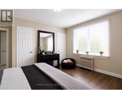 A bedroom with a large bed and a window with blinds.