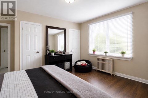 A bedroom with a large bed and a window with blinds.