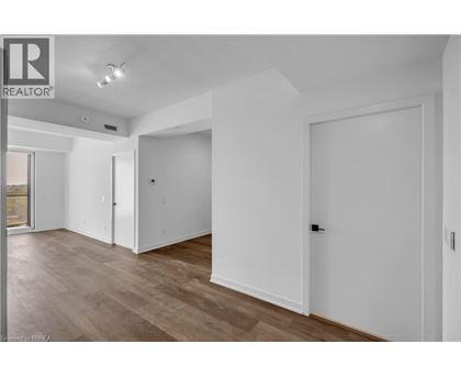 A spacious room with wooden flooring and white walls.