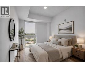 A bedroom with a large bed, a side table with a lamp, and a framed picture on the wall.