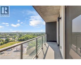 A balcony with a glass railing overlooking a parking lot and trees.