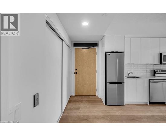 A kitchen with white cabinets and a wooden door.