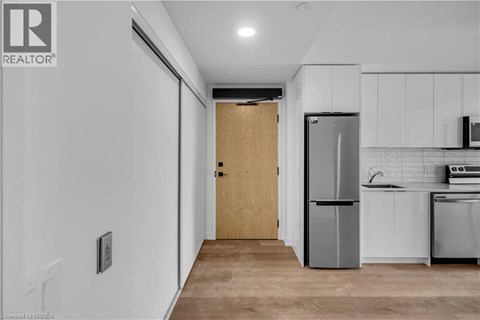 A kitchen with white cabinets and a wooden door.