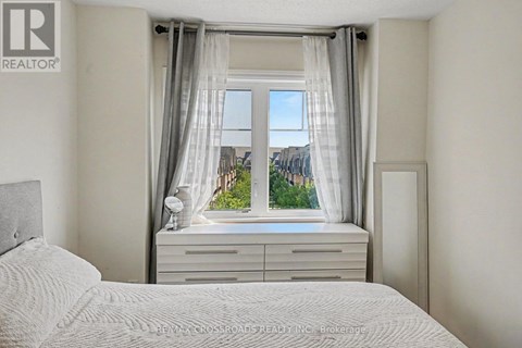 A bedroom with a large bed and a window with curtains.