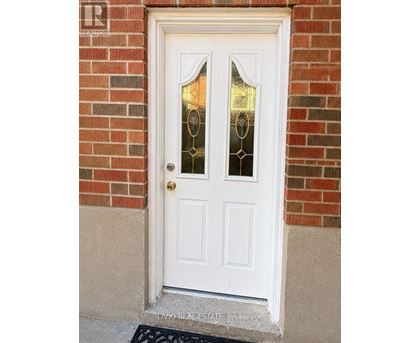 A white door with glass panels and a gold doorknob is set in a brick wall.