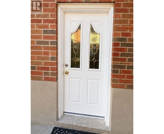 A white door with glass panels and a gold doorknob is set in a brick wall.
