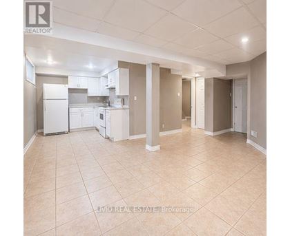 A spacious kitchen and living room with beige tiled flooring and white appliances.