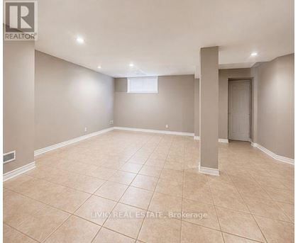 A spacious empty room with beige tiled flooring and white walls.