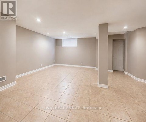 A spacious empty room with beige tiled flooring and white walls.