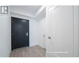 A black door is in a white room with a wooden floor.