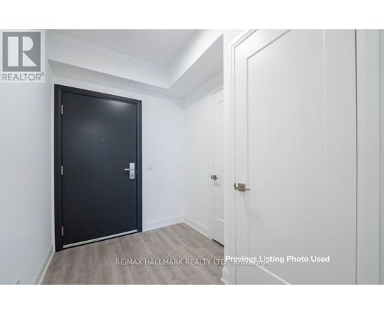 A black door is in a white room with a wooden floor.