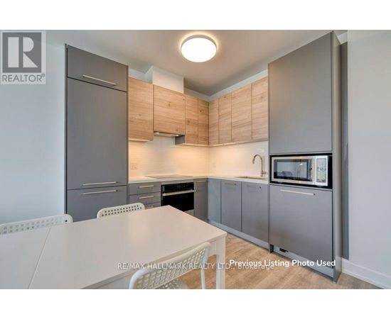 A kitchen with a table and chairs in front of a refrigerator and microwave.