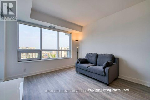 A living room with a grey couch and a large window.