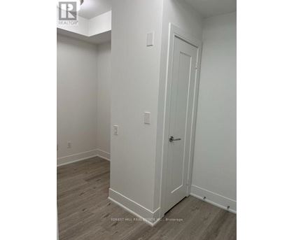 A white door is on the right side of a room with wood flooring.