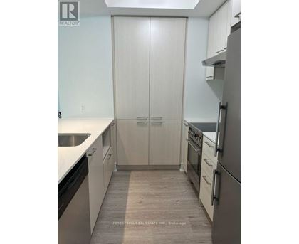 A kitchen with white cabinets and a refrigerator.