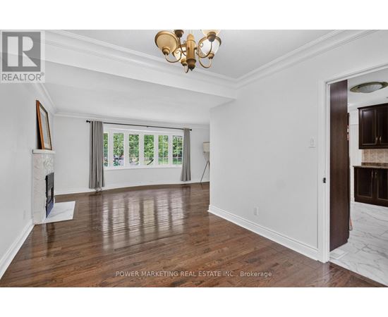 A room with a chandelier, a painting, and a window with a view of trees.