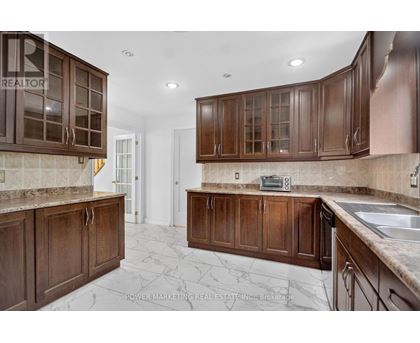 A kitchen with brown cabinets and a marble floor.