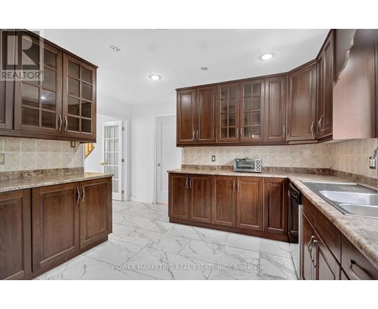 A kitchen with brown cabinets and a marble floor.