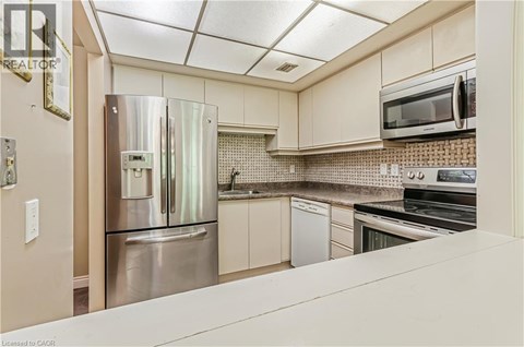 A kitchen with a stainless steel refrigerator and white cabinets.