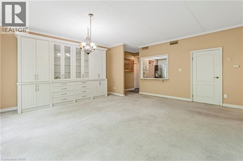 A spacious room with a chandelier and a cabinet with glass doors.