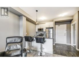 A modern kitchen with a bar stool and a black leather chair.