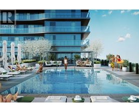 A group of people are enjoying the sun by a pool in front of a modern building.