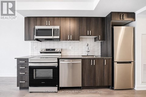 A modern kitchen with dark wood cabinets and stainless steel appliances.
