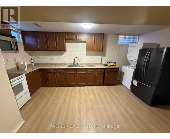 A kitchen with wooden cabinets and a black refrigerator.