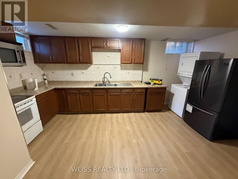 A kitchen with wooden cabinets and a black refrigerator.