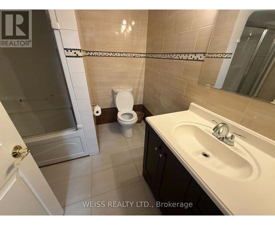 A bathroom with a toilet, sink, and mirror.