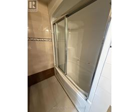 A shower area with a glass door and tiled walls.