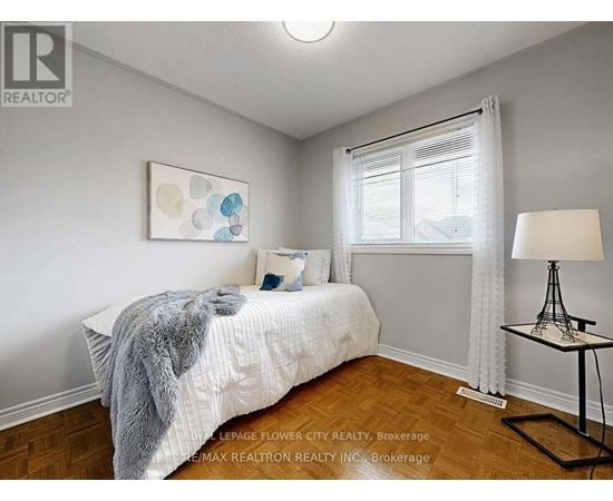A bedroom with a bed, a lamp, and a painting on the wall.