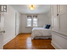 A bedroom with a bed, a window, and a wooden floor.
