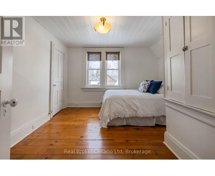 A bedroom with a bed, a window, and a wooden floor.