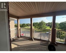 A balcony with a metal railing and a view of a street and trees.