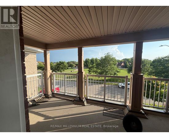 A balcony with a metal railing and a view of a street and trees.