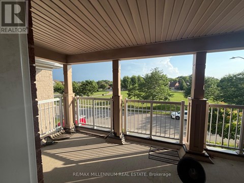 A balcony with a metal railing and a view of a street and trees.
