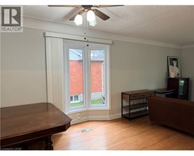 A room with a brown table and a brown couch with a window and a fan.