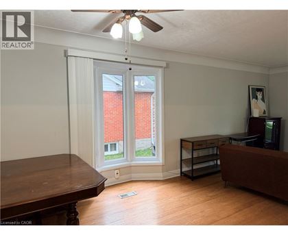 A room with a brown table and a brown couch with a window and a fan.