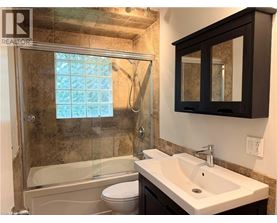A bathroom with a white sink, a toilet, and a glass shower stall.