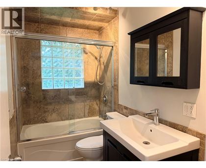 A bathroom with a white sink, a toilet, and a glass shower stall.