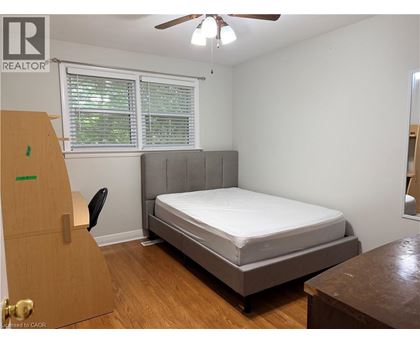 A bedroom with a bed, dresser, and window.